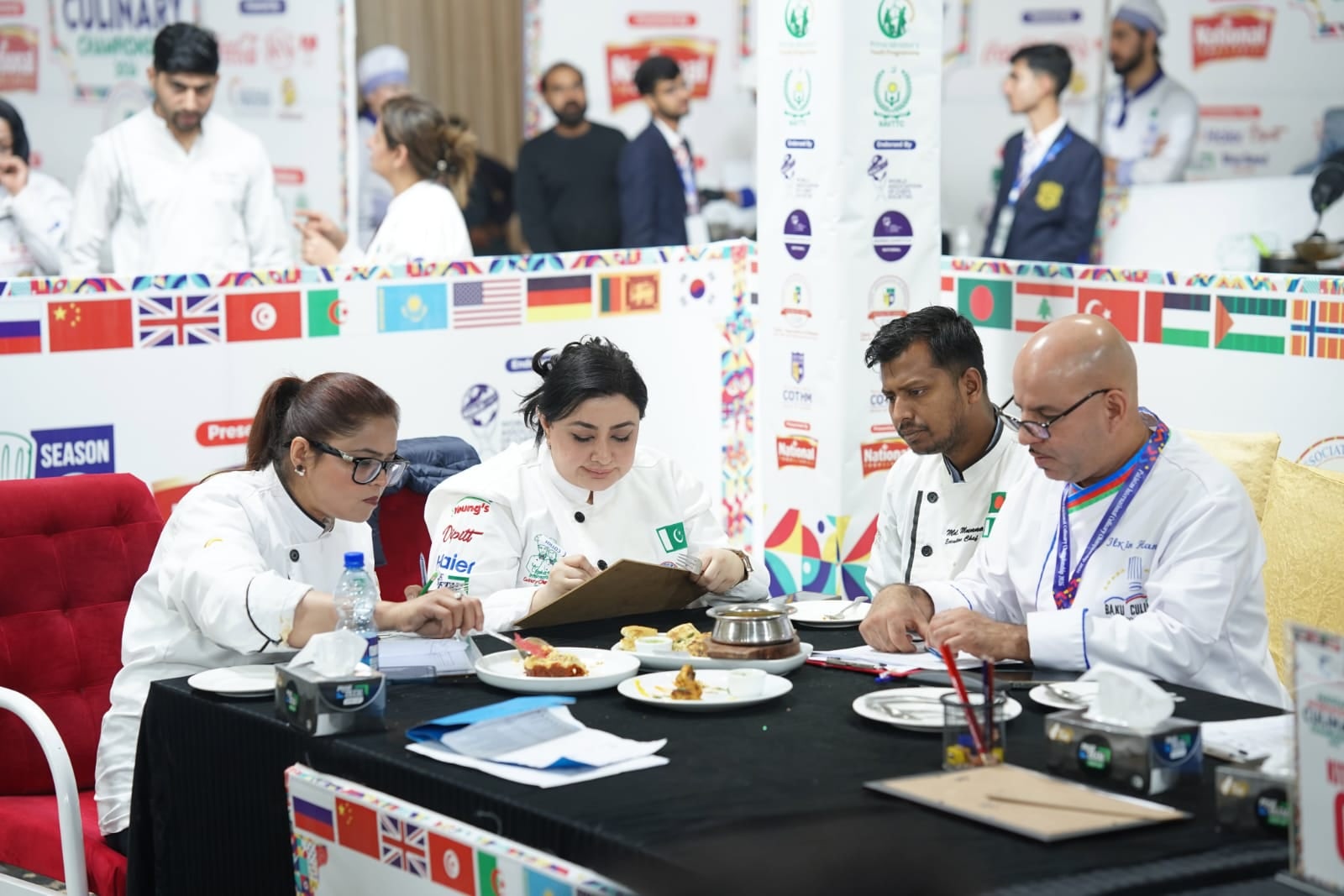 Chef Munna seated with judges reviewing competition plates at a culinary championship table