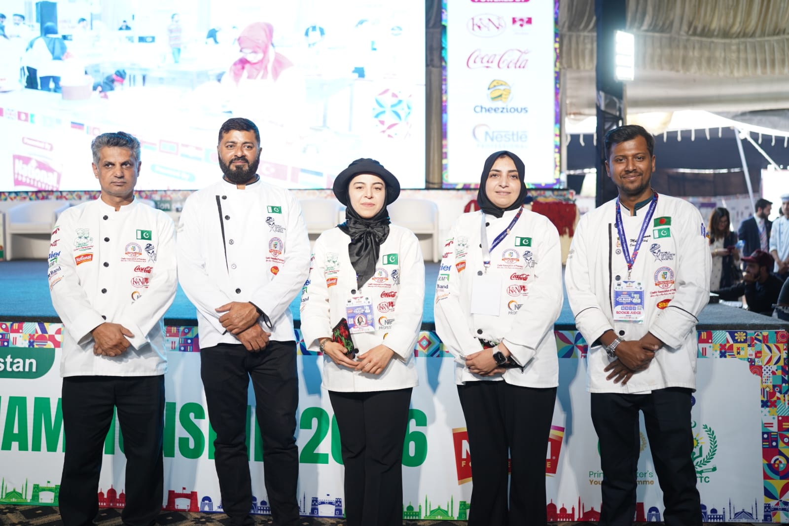 Chef Munna standing with an international chef delegation in front of a competition stage backdrop