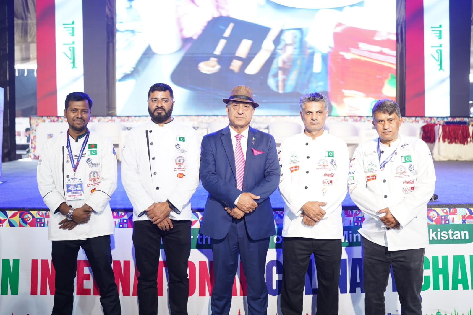Chef Munna standing with international delegates holding national flags at a culinary event