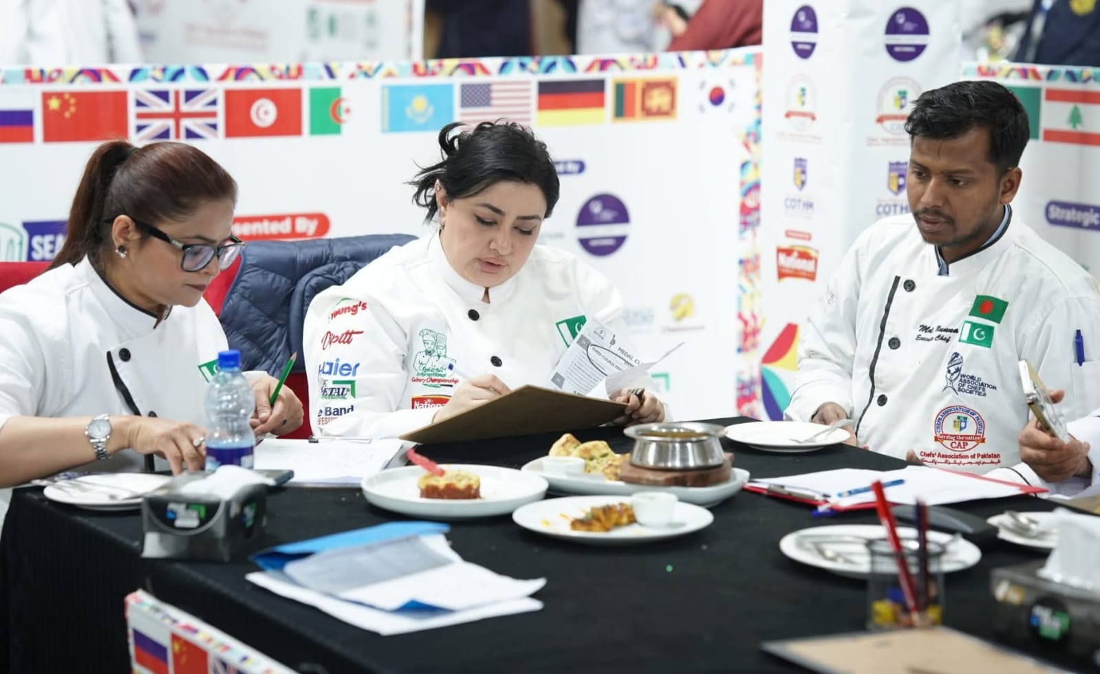 Chef Munna seated with fellow judges while evaluating dishes during a culinary championship